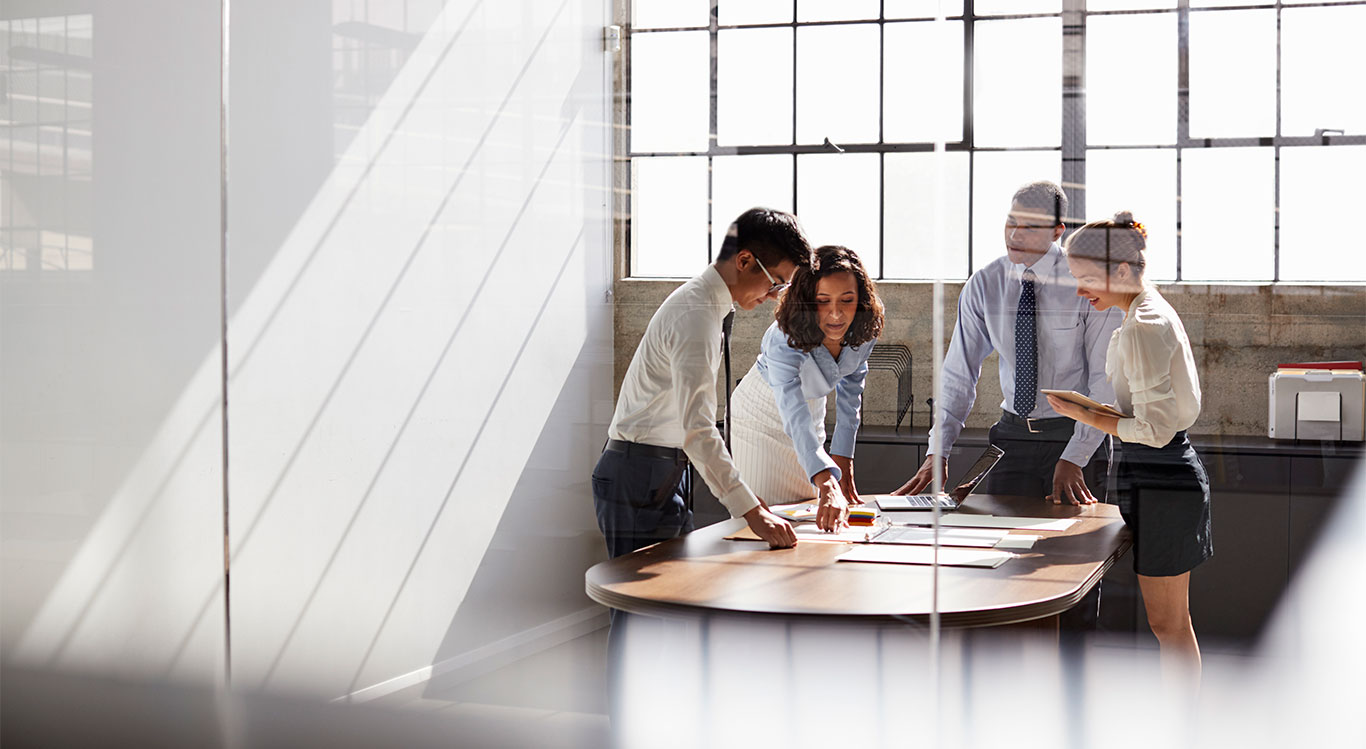 group of people standing around conference table